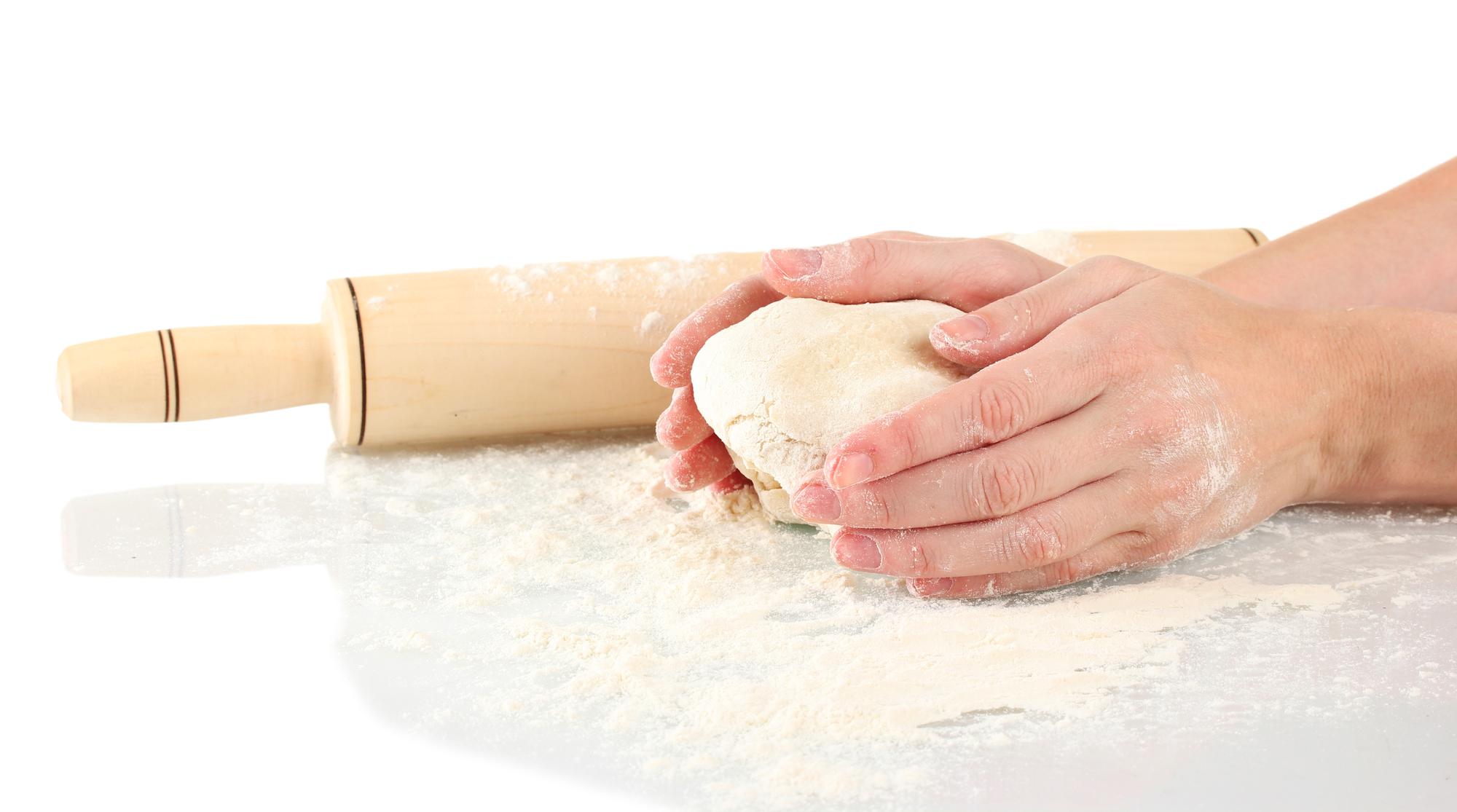 Workshop hands kneading dough on wooden table